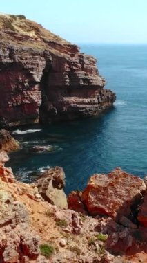 Turkuaz denizin üzerindeki engebeli kızıl kayalıklar, hava temizliği yalnız deniz yığınlarını, temiz su birikintilerini ortaya çıkarıyor.