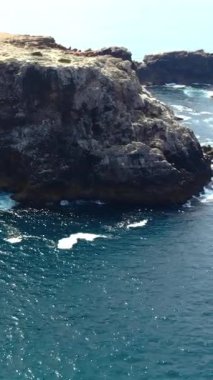 Sivri deniz yığınları ve kayalık çıkıntıları, turkuaz dalgalar ve engebeli platoyla hava dramatik bir promonktur.,