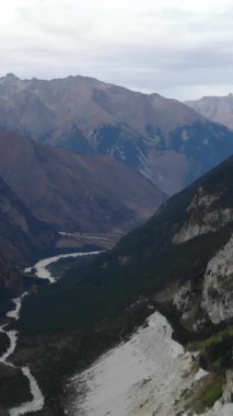 Bulutlu bir günde derin bir dağ geçidinde akan dolambaçlı bir nehrin görkemli hava perspektifi. Medya