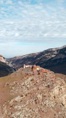 İnsansız hava aracı, dağ vadisindeki bir uçurumun tepesindeki terk edilmiş eski bir taş binanın üzerinde uçuyor. Medya
