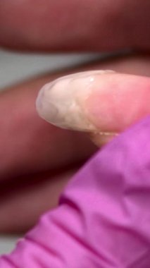 Yakından İnce boncuklar takan ve düzleştiren Eldiven Teknisyenini gösteren Tırnak Uzantısı Yapıcı Jel. Medya