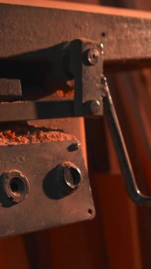 Kontrol kutusu, makinenin alt sınırında odun talaşı, kırmızı düğme ve düğmeler görünür, sıcak Amber ışığı ile dolu. Medya