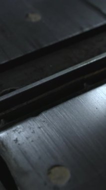 Merkezi tutkal ve cıvata delikleriyle metal masa yerleştirme, ince yansımalar, talaş parçacıkları ve aşınmış atölye. Medya