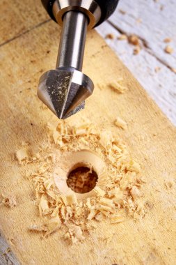 Çelik matkaplar ve tezgahlarla ahşabı delmek. Küçük marangozluk atölyesinde çalışıyor. Hafif arkaplan.