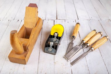 Ahşap bir masada iki ahşap planör ve bir keski. Ev atölyesinde marangoz aksesuarları. Hafif arkaplan.