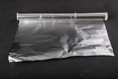 Karton silindirde alüminyum folyo yarası. Yiyecek depolamak için kullanılan malzeme. Koyu arkaplan.