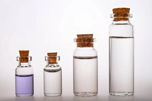 Glass bottles with liquid closed with a stopper. Container for storing liquids. Light background.