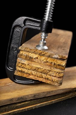 Tahtayı yapıştırmak için küçük siyah joinery klempi. Atölyede çalışmak için marangoz aksesuarları. Koyu arkaplan.