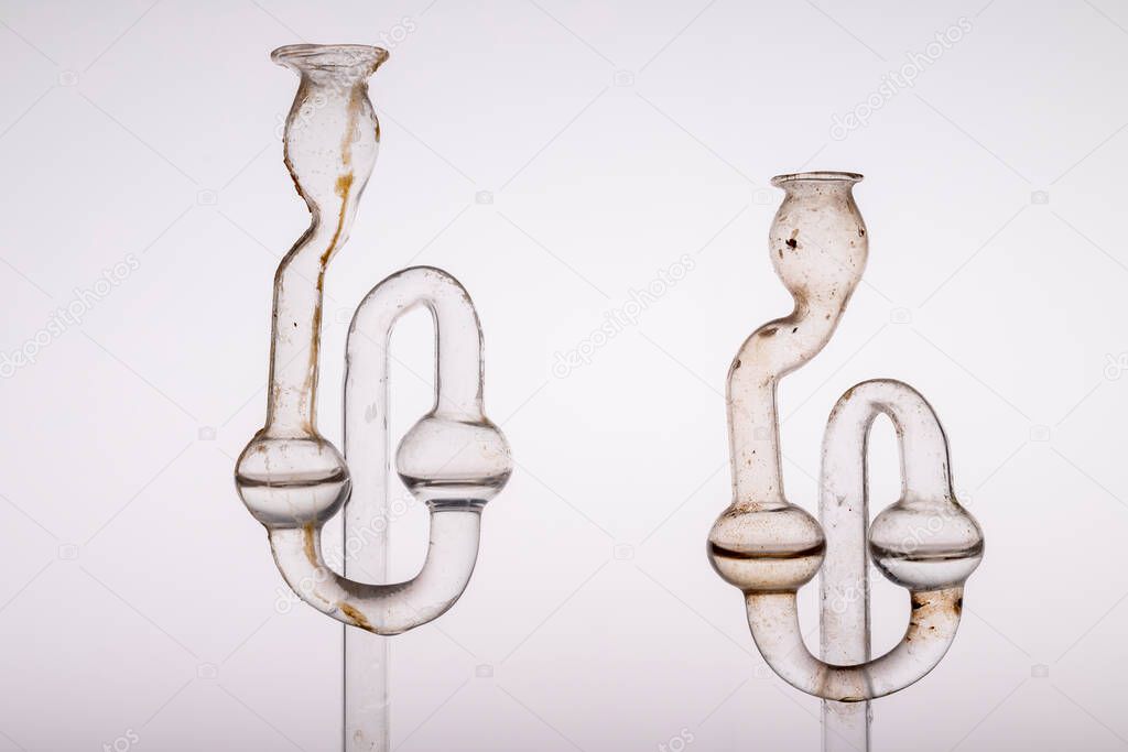 Old dirty fermentation tube. Glass accessories for wine fermentation. Light background.