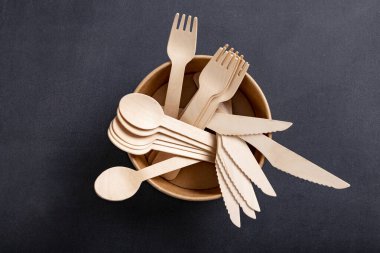 Masada ahşap çatal bıçak takımı var. Fast food barında kullanılan aletler. Koyu arkaplan.