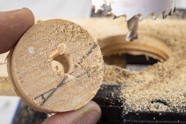 Tahtada büyük bir delik açmak. Masa matkabında kullanılan delik testeresi. Koyu arkaplan.