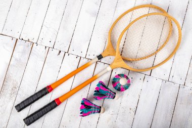 Badminton mekik horozları ve tahta kürekler. Ahşap bir masada amatör oyunlar için aksesuarlar. Hafif arkaplan.