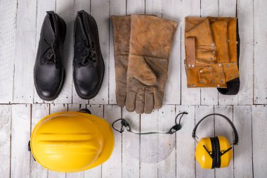 Beyaz masadaki bir prodüksiyon işçisi için giysi. İş yerinde kullanılan kişisel koruyucu aksesuarlar. Hafif arkaplan.