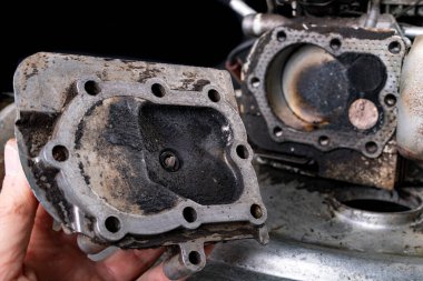 Çim biçme makinesinden çıkan küçük bir içten yanmalı motorun tamiri. 4 vuruşluk motorun baş, silindir ve pistonu. Koyu arkaplan.