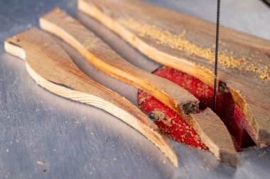 Masa testeresiyle odun kesmek. Tahta bir tahtanın içinde karmaşık şekiller kesmek. Atölye çalışma yeri.