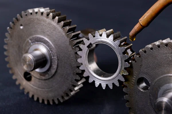 Coating gears with oil. Accessories and spare parts for industrial machinery. Dark background.