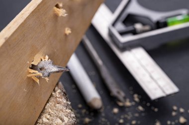 Bir odun parçasını metal matkapla delmek. Küçük marangozluk atölyesinde çalışıyor. Koyu arkaplan.