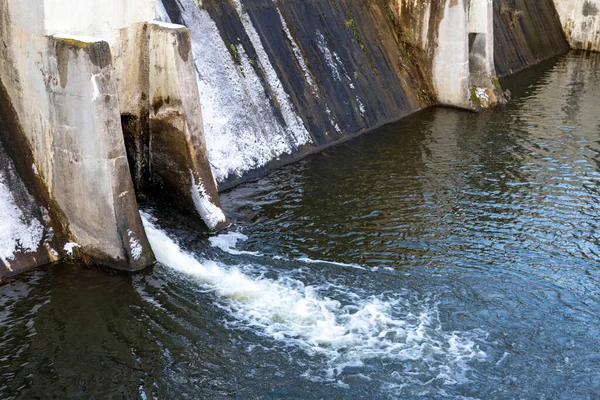 Water drain in a small dam. View of the overflow channel in the hydrotechnical structure. Winter season.