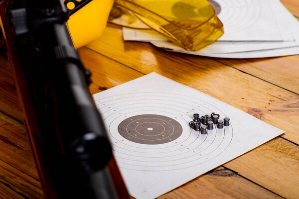 Пневматическое оружие и аксессуары для стрельбы. Слуховые щиты на стрельбище. Темный фон.
