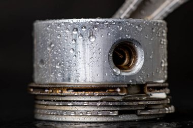 İçten yanmalı motorun pistonuna su damlıyor. İçten yanmalı motor için ıslak yedek parçalar. Koyu arkaplan.