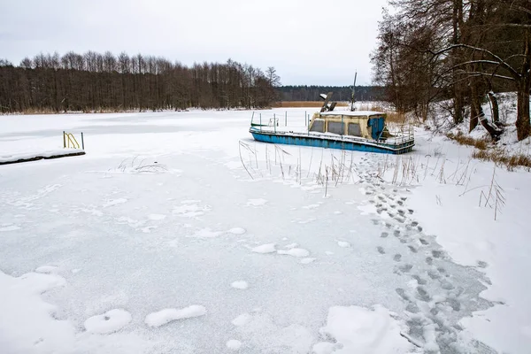A large boat trapped in ice on a lake. A frozen lake in a boat dock. Winter season.