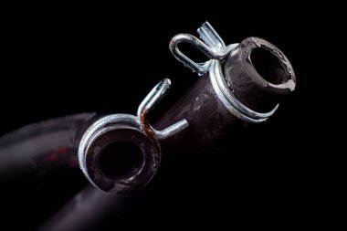 Metal kıskacı olan ıslak siyah bir hortum. Su ve kanalizasyon sistemlerini yenileyen tesisatçılar için aksesuarlar ve yedek parçalar. Siyah arkaplan.