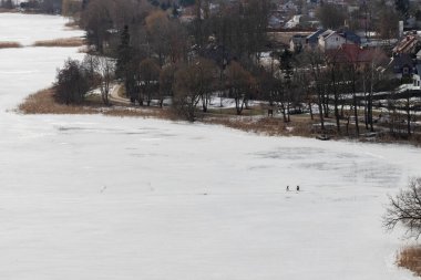 Balıkçı donmuş gölde balık tutuyor. Kocaman bir su deposunun arka planında bir adamın küçük bir silueti. Kış mevsimi.