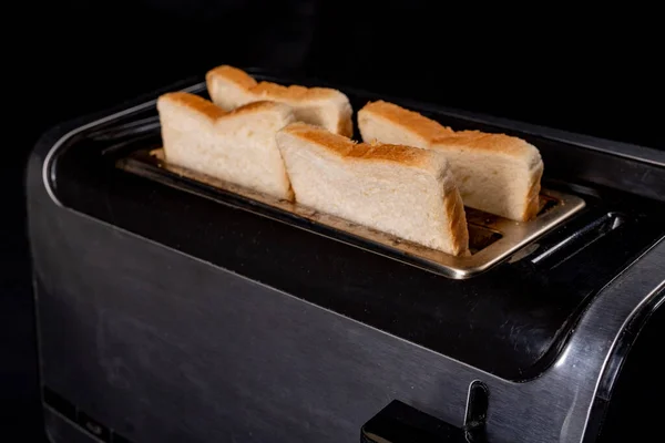 A modern toaster for toasting bread. Domestic electrical appliance for making casseroles. Dark background.