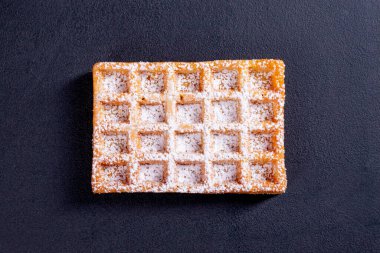 Tatlı waffle 'lar servis için hazırlanmış pudra şekeri serpiştirilmiş. Meyve ve reçelli lezzetli bir tatlı. Koyu arkaplan.