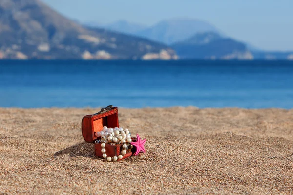 Coffre décoratif avec bijoux et étoiles de mer sur une plage — Photo