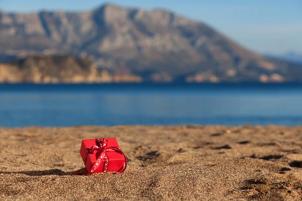 Scatola regalo rossa su una spiaggia — Foto Stock