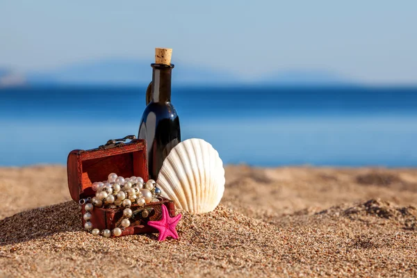 Pecho decorativo con joyas, botella y estrella de mar en una playa —  Fotos de Stock