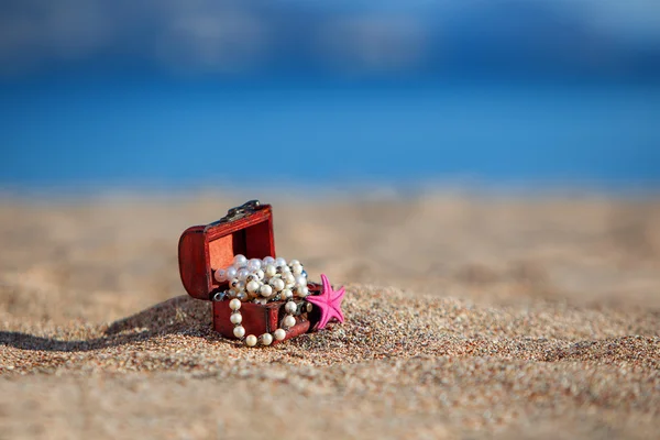 Comò decorativo con gioielli e stelle marine su una spiaggia — Foto Stock