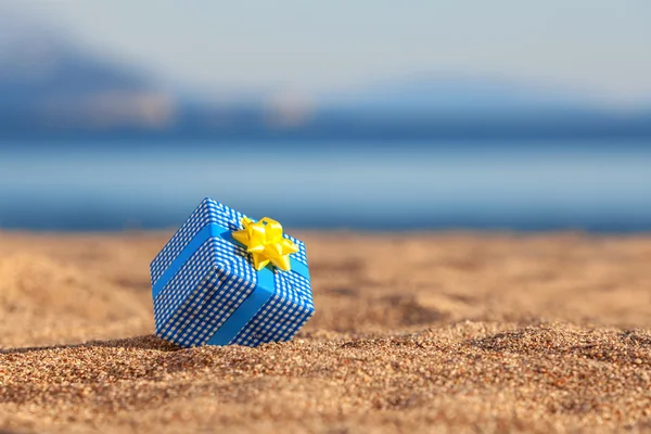 Scatola regalo blu su una spiaggia — Foto Stock