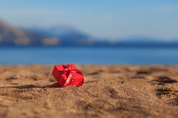 Scatola regalo rossa su una spiaggia — Foto Stock