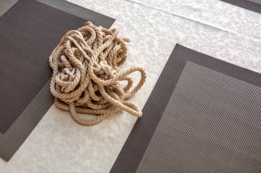 Denizcilik halatı masanın üzerinde iki peçete arasındaki masa örtüsünün üzerinde yatıyor. Kazara terk edilmiş.