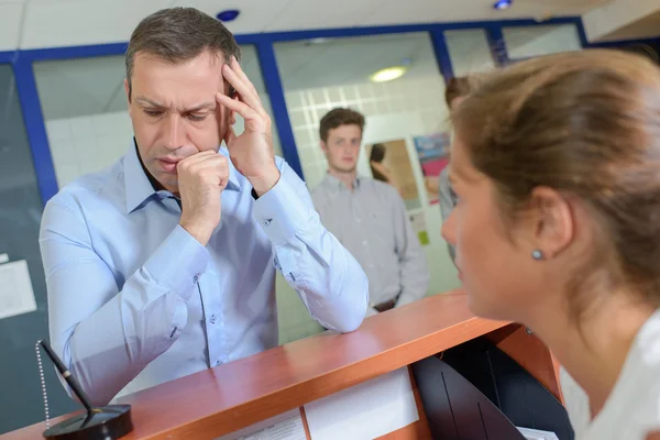 Man at reception desk, in pain — Stock Photo, Image