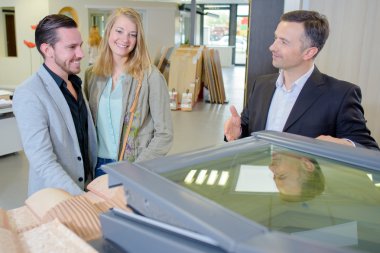 Salesman showing couple an opening roof light clipart