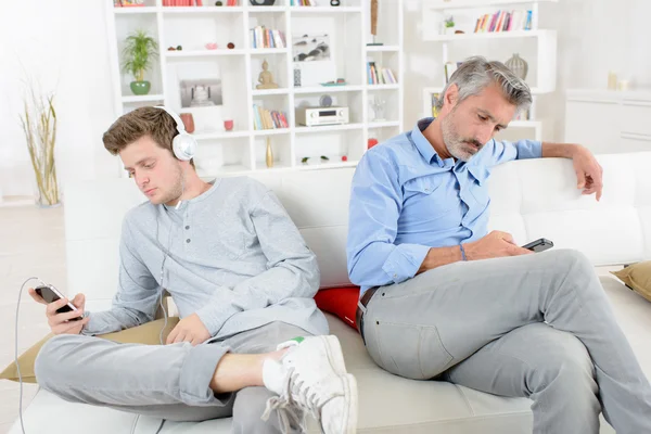 Adult and adolescent independetly using their electronic devices — Stock Photo, Image