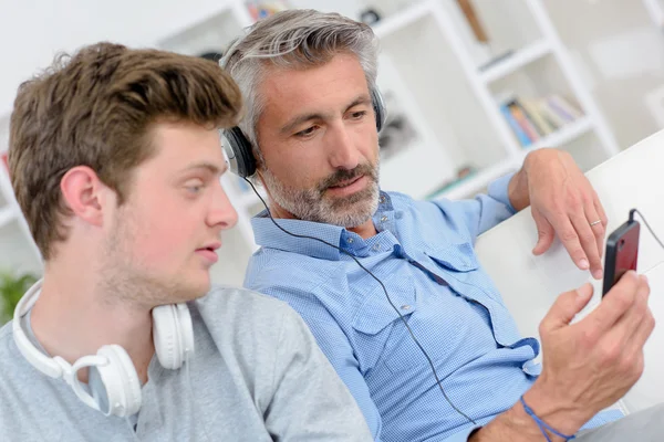 Far och son lyssnar på musik i hörlurar — Stockfoto