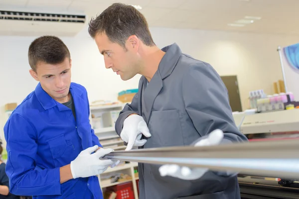 Uomini con un tubo metallico — Foto Stock