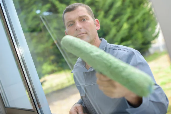 Mann putzt eine Fensterscheibe — Stockfoto