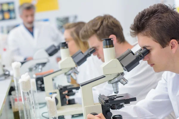 Estudiantes usando microscopios y estudiantes — Foto de Stock