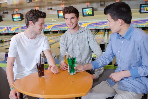 Três jovens tomando uma bebida na pista de bowling — Fotografia de Stock