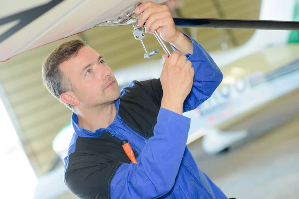 Man aan het werk aan de onderzijde van een vliegtuig — Stockfoto