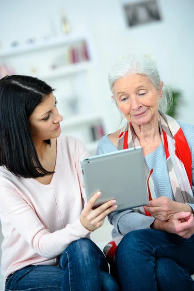 Mädchen hilft Seniorin beim Lesen — Stockfoto