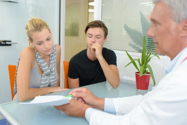 Doctor with couple, pointing to paperwork — Stock Photo, Image