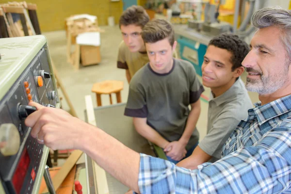 Teacher showing students how to use machinery — Stock Photo, Image
