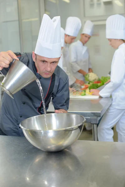 Chef derramando líquido em tigela de aço inoxidável — Fotografia de Stock