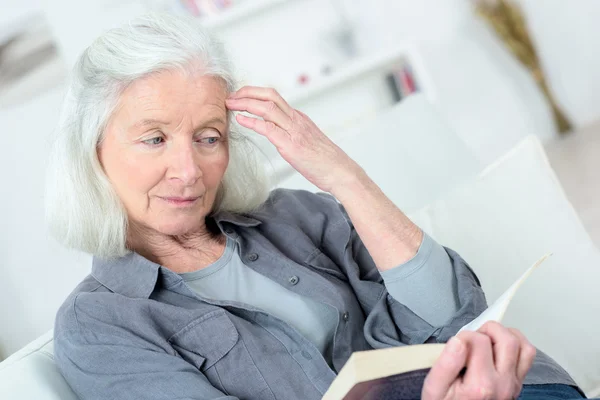 늙은 여자는 소파에 읽기 — 스톡 사진